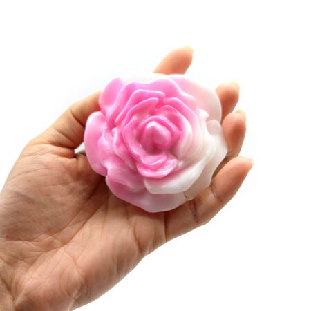 Hand holding the pink rose shaped silicone grinder from Uberrime