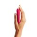 Hand holding a cherry Red colored We-Vibe Tango X bullet vibrator straight up on a white background