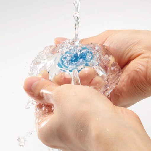 Water running down a Tenga Aero Cobalt Masterbater while hands clean them